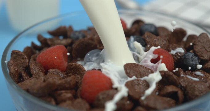 Milk pouring into bowl with chocolate corn flakes with splash in super slow motion 1000 fps