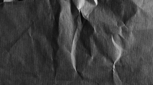 Abstract black crumpled paper texture background, with subtle light movement