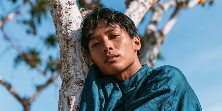 Young man portrait leaning on tree outdoors for editorial portrait background and lifestyle banner design
