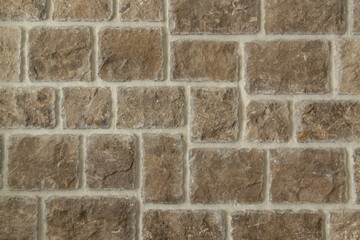 Fototapeta premium Brown stone wall texture background closeup. Decorative stone tiles background with light seams