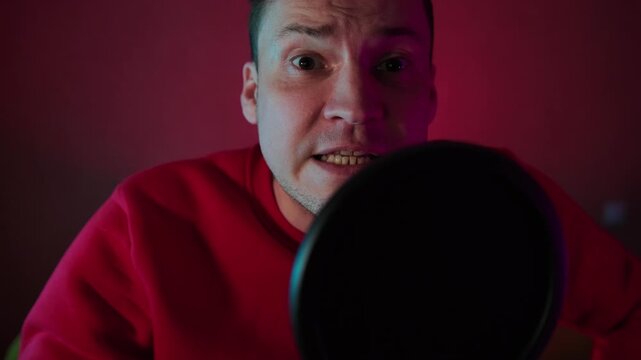 Man talking into a recording microphone. Podcaster recording audio in a studio. Digital content creator speaking to an audience. Communication and media concept