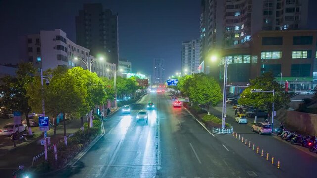 Illuminated urban boulevard with cars and apartment buildings at night