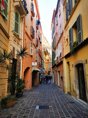 Fototapeta premium Monaco old town narrow street with colorful buildings and perspective view. Scene represents travel, culture, architecture, and historic urban lifestyle concept.
