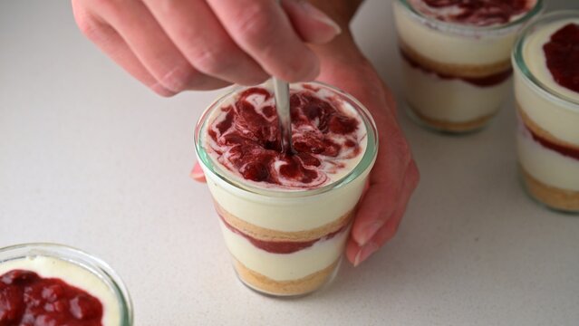 Homemade cottage cheese (farmers cheese) dessert cup layered with vanilla cookie crumbs and strawberry confit sauce. Creamy no-bake cheesecake style dessert in a glass cup with berry topping.