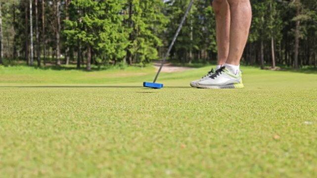 Putting practice on the golf course in a sunny afternoon with a focus on the player and the golf ball
