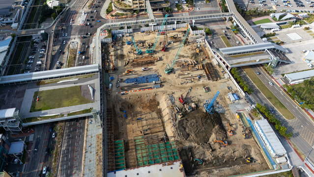 Aerial view of a large construction site with cranes, excavators, and foundation work in progress, surrounded by roads and pedestrian walkways in Busan, Busan, South Korea.