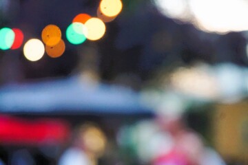 Obraz premium Abstraktes Motiv von Sommerfest mit bunten runden Lichtern über blauem Zeltdach und Gästen in Stadt am Abend im Sommer