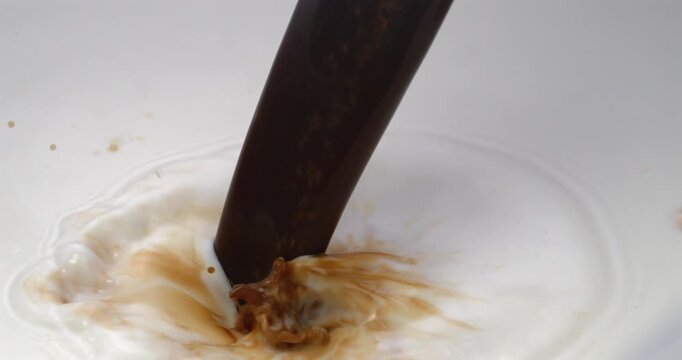 Fresh brewed coffee pouring into milk creating latte in super slow motion 1000 fps