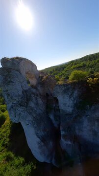 Cinematic FPV drone flight through a natural rock arch at Maczuga Herkulesa in southern Poland. Unique limestone formation surrounded by forest in the Jura region.