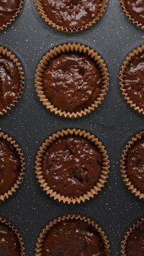 Double chocolate muffin batter in paper liners in baking tray before baking. Food photography. Homemade bakery, pastry and baking process concept. Top view close-up shot.