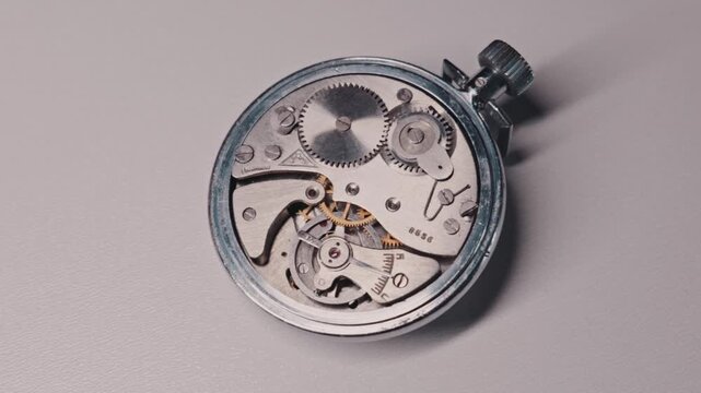 Close-up view of an open vintage mechanical stopwatch mechanism with moving gears and oscillating balance wheel. Concept represents precision engineering, timekeeping, and complex mechanics.