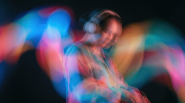 Asian woman DJ wearing headphones in colorful night light