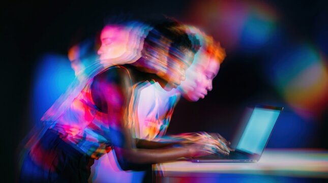 Black man using laptop with colorful light effects at night