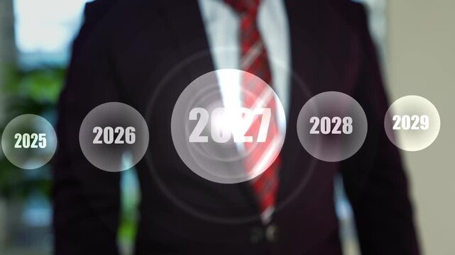 Businessman in suit touching glowing holographic 2027 icon among future years