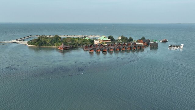 Aerial view of Pulau Lima Resort featuring traditional wooden bungalows over the water, lush tropical vegetation, and clear blue sea in Kasemen, Banten, Indonesia.