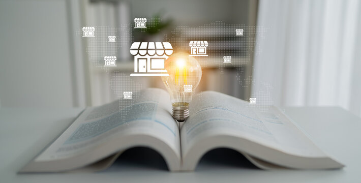 An open book rests on a table, featuring a glowing light bulb symbolizing ideas, surrounded by digital store icons that illustrate online business opportunities. Gantry