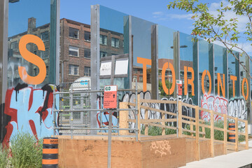 Naklejka premium transparent noise barrier wall with sign at West Toronto Rail Path, garden area near Ernest Av