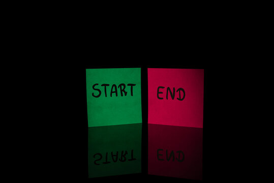Green sticky note START next to red sticky note END on black background with reflection. Concept of beginning and ending, project lifecycle and business cycle.