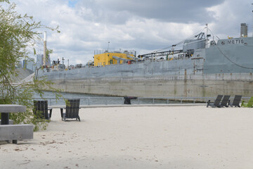Fototapeta premium decommissioned bulk carrier, Metis (built, 1977) now a stationary storage vessel, docked at Ship Channel, viewed from Leslie Lookout Park, Port Lands, Toronto