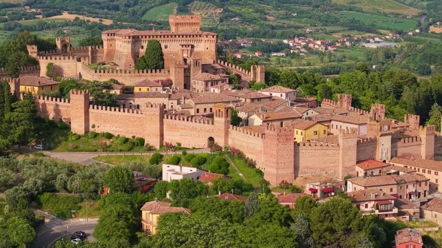 Gradara Marche Italy 4k drone 70mm telephoto side tracking flight of entire borgo. Castle walls fortress revealing historic medieval townscape over green fields rolling hills b-roll