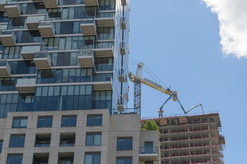 Fototapeta premium distant view of a concrete pump boom hose at Pinnacle Lakeside with view of Monde Condominiums, Toronto