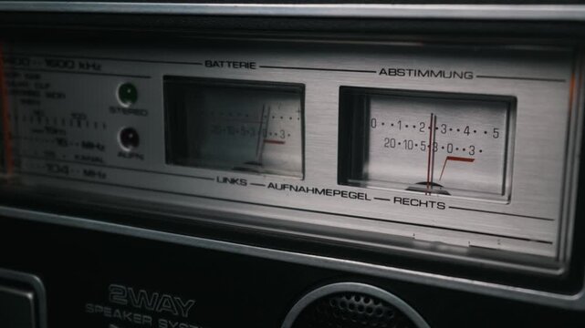 Retro silver boombox interface featuring analog needle VU meters and radio frequency tuning dials. Concept of vintage music nostalgia, analog audio technology, and classic stereo entertainment.