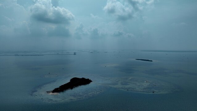 Aerial view of Pulau Lima Resort surrounded by calm blue waters and scattered small islands under a cloudy sky in Kasemen, Banten, Indonesia.