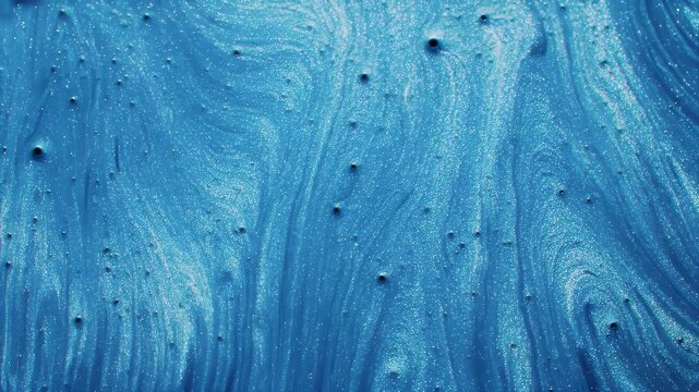 Abstract swirls of blue metallic paint with small bubbles.