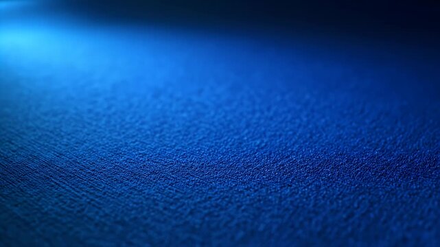 A close-up, abstract shot of a textured dark blue surface illuminated by soft blue light.