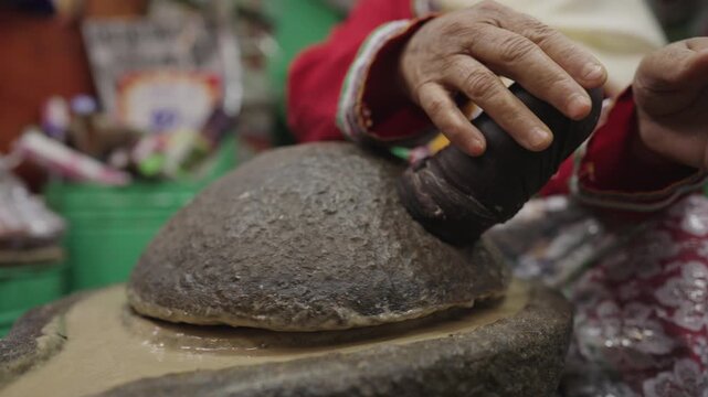 Traditional Moroccan Amlou preparation using a stone grinder at Jemaa El Fna Square in Marrakech, Morocco 2025. Authentic food-making process showcasing local culture.