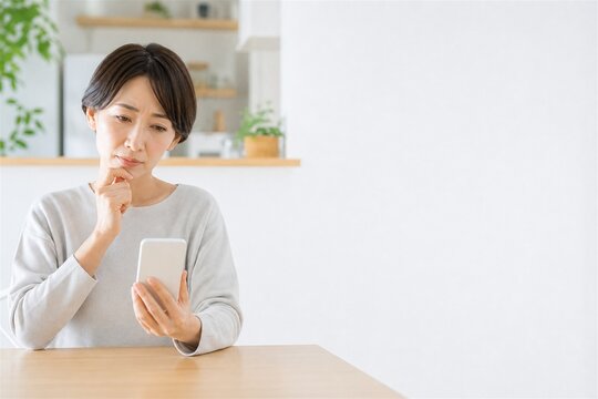 スマホを見つめる保護者と明るいキッチン余白