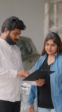 Indian car salesman explaining contract to female customer