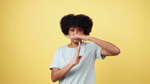 Woman showing time out hand gesture on yellow background