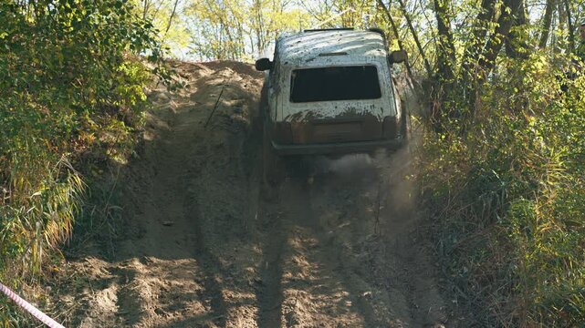 A shot captured in motion: a powerful SUV climbs a challenging sandy slope during an off-road race. The vehicle struggles to overcome the extreme terrain in a sunny forest. Adrenaline, power concept