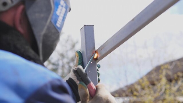 Fabricator Welding Crossbeam For Gate Assembly Outdoors, Steady Hand And Torch Angle, Gloves Holding Post, Small Workshop Tools And Rural Background, Methodical Construction Step