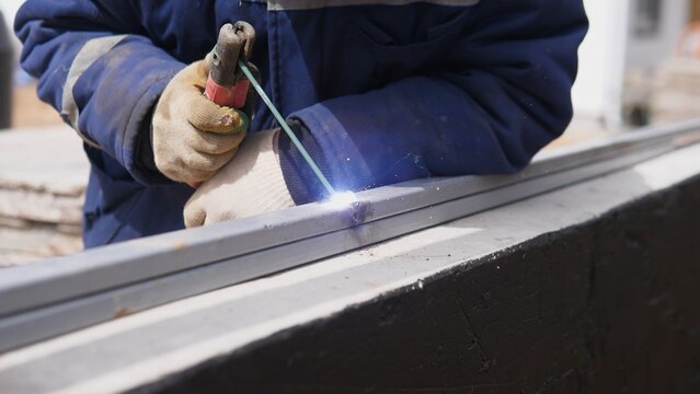 Closeup Fabricator Using Welding Torch On Metal Frame, Sparks And Heat At Joint, Gloved Hands Steadying Fixture, Workshop And Onsite Assembly Combined In Practical Fabrication Scene