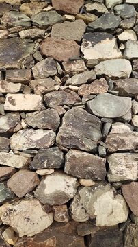Natural rock and stone wall background displaying a rugged and solid texture. The earthy tones of the ancient stones create a beautiful abstract pattern perfect for architectural projects