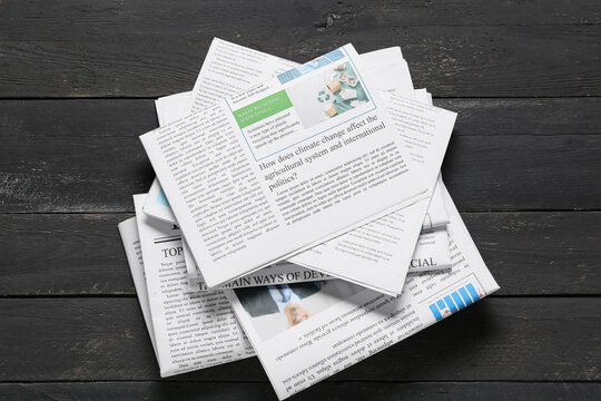 Stack of newspapers with climate change and recycling headlines on dark wooden table global news and information, this arrangement highlights the importance of staying informed about environmental