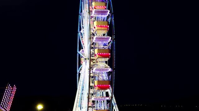 Illuminated Ferris Wheel Spinning At Night Amusement Park. Colorful Neon Lights Performance. Evening Entertainment Presentation