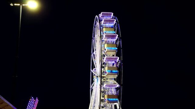 Illuminated Ferris Wheel Rotating At Amusement Park In Darkness. Neon Glowing. Evening Leisure