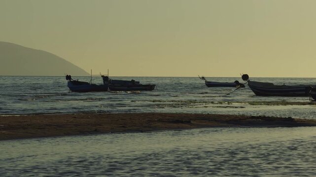 Fishing Boats Near Sandy Beach At Sunset. Small Vessels On Waves In Evening Sunlight