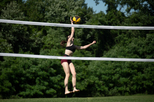 young woman playing doubles grass volleyball hitting the ball above the net