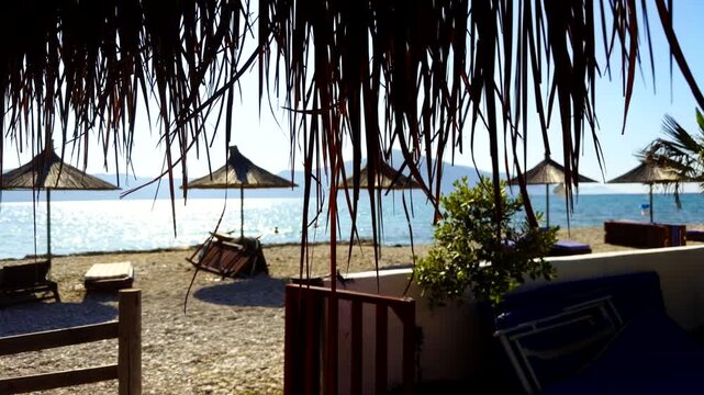 Empty Pebble Beach With Straw Umbrellas. Summer Resort Coast. Seaside Vacation