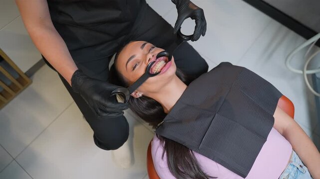 Dentist inserting retractor into woman's mouth