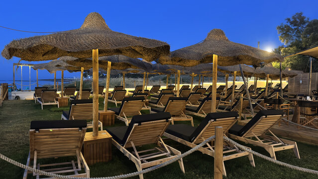 Luxury Beach Sun Loungers Under Thatched Parasols at Blue Hour by the Sea
