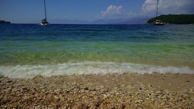 Clear Turquoise Sea Water. Waves Washing Sandy Pebble Beach. Sailing Yachts Anchored In Bay