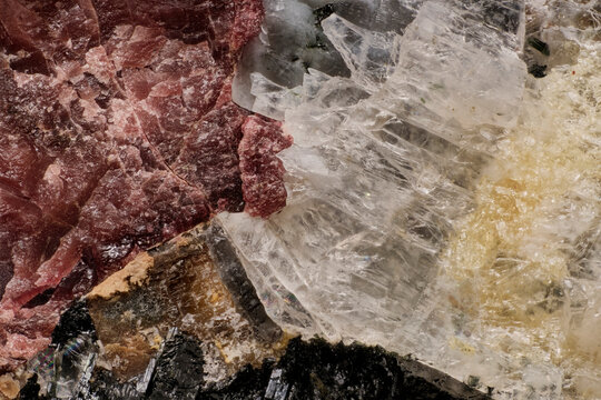 Macro image of rare minerals captured with 5X microscope objective lens: pink eudialyte, dark loparite and yellow titanite crystals in Khibiny rock