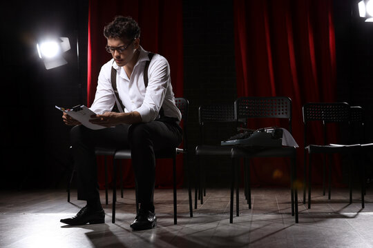 Male screenwriter reading scenario in chair on scene