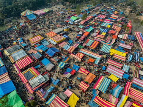 Aerial view of a bustling outdoor market featuring rows of colorful tents, a carousel, and crowds of people walking through the fairgrounds in Bogura, Rajshahi Division, Bangladesh.