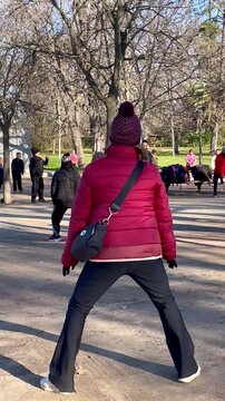 Ejercicio tercera edad actividad f&iacute;sica mayores viejo activo saludable estiramiento y flexibilidad en grupo y monitor mujer de espaldas aire libre parque 